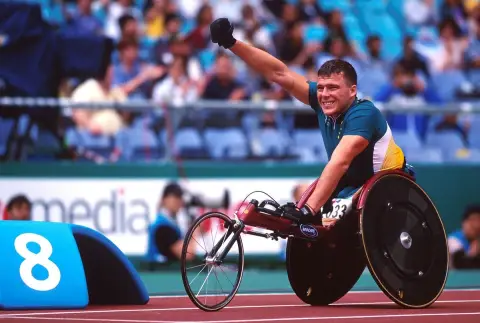 Wheelchair racer Kurt Fearnley waves to the crowd from his racing chair in the stadium at the 2000 Sydney Paralympic Games.