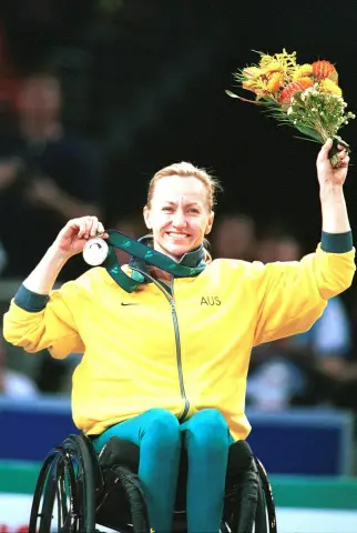 Wheelchair basketballer Donna Ritchie beams and raises a bouquet and her silver medal at the 2000 Sydney Paralympic Games.